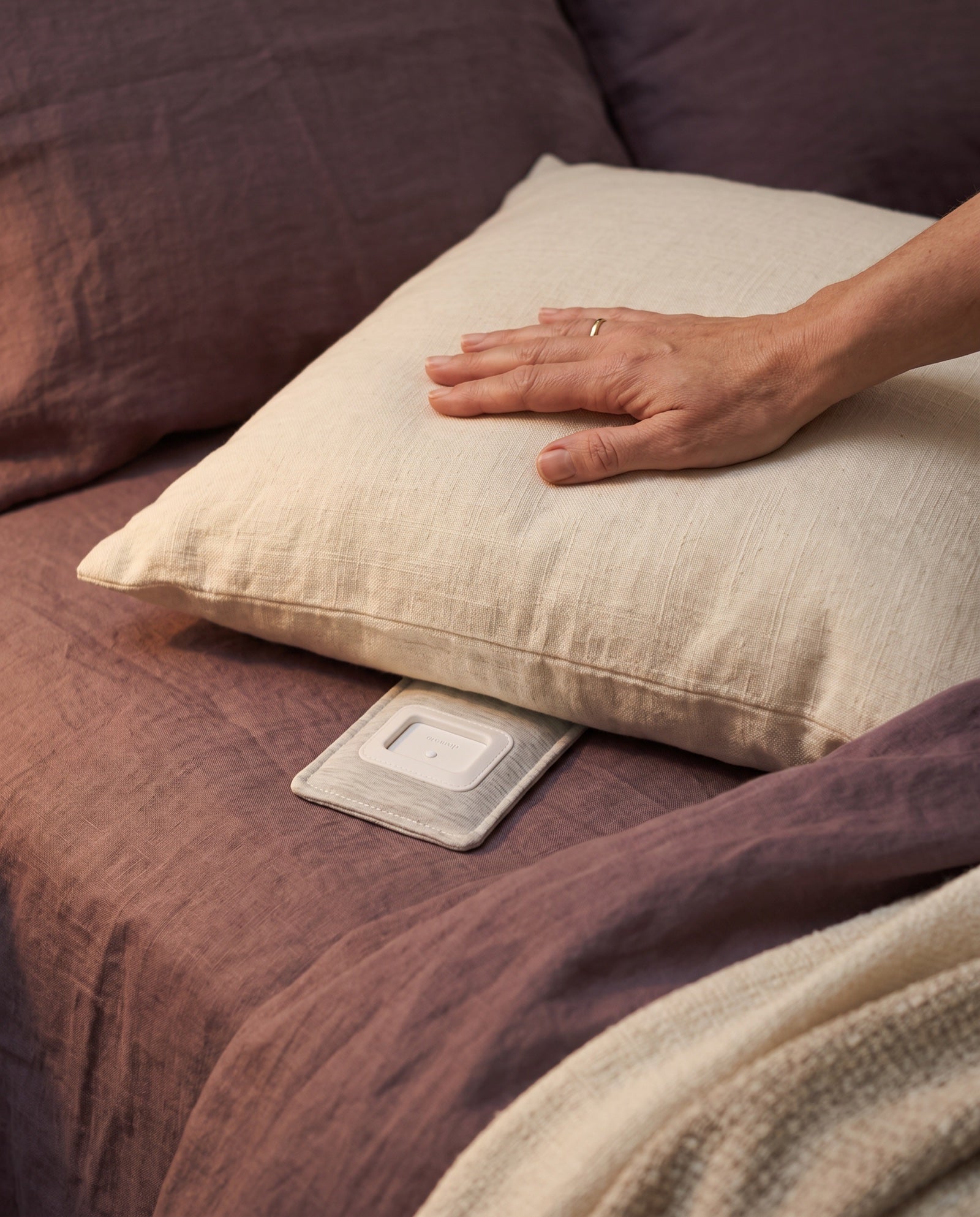 A hand resting on the pillow with the Drowsie flat underneath it